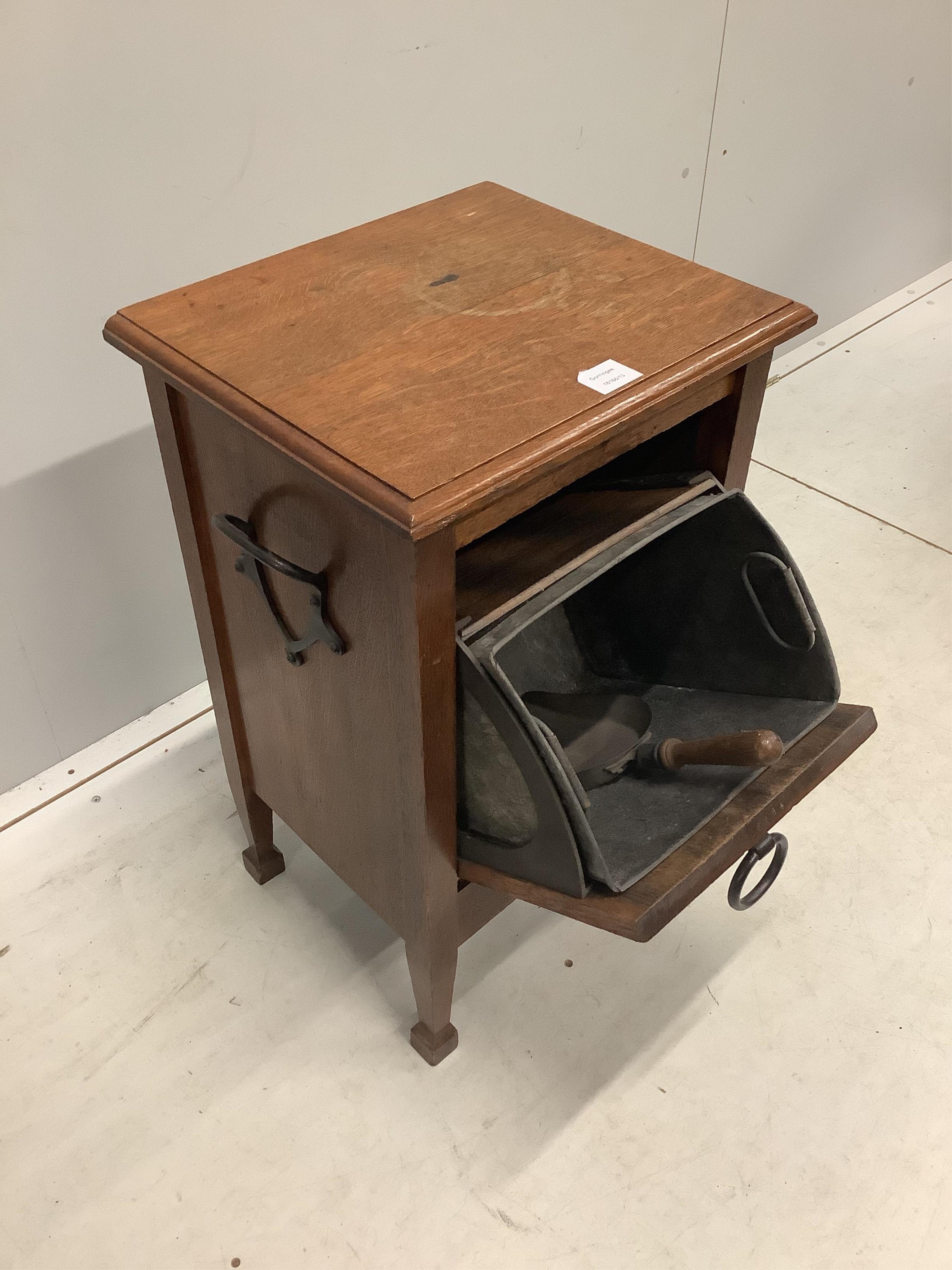 An Arts and Crafts oak coal purdonium, the fall front with a wrought iron handle and side carrying handles, together with a liner and shovel, width 42cm, depth 36cm, height 70cm. Condition - poor to fair